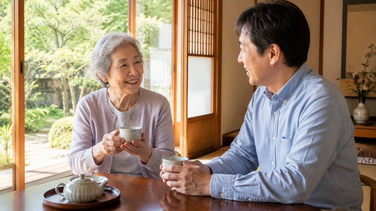 和室の縁側で高齢の母と息子がお茶を飲みながら笑顔で話している様子